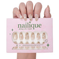 Short almond press-on nails by nailique with white floral design, gold foil accents, reusable tips, and lamp-curable glue.