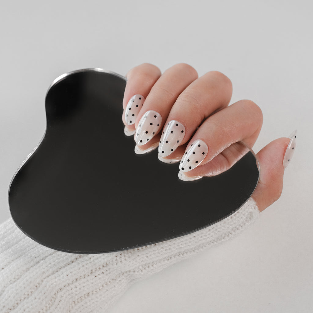 Handmade Nailique short almond press-on nails with chrome glaze, white and black polka dots, soft gel finish.