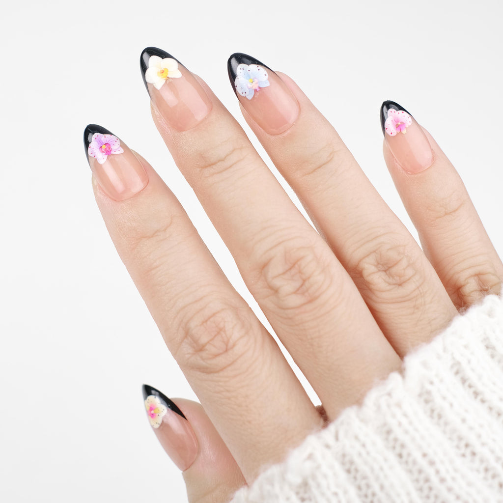 Short almond press on nails by Nailique with black French tips, 3D orchid flower art, reusable gel nail tips, and salon-quality finish