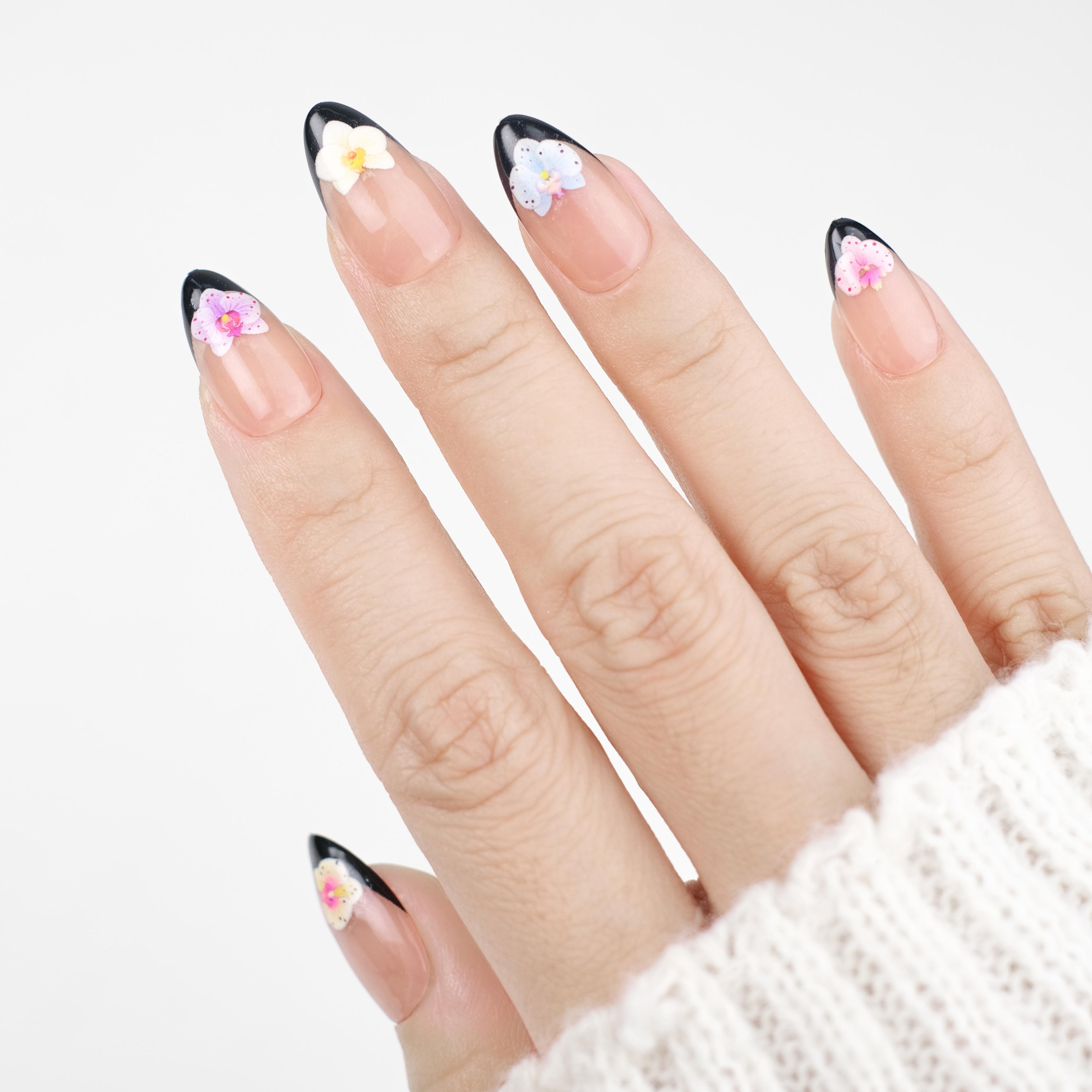 Short almond press on nails by Nailique with black French tips, 3D orchid flower art, reusable gel nail tips, and salon-quality finish