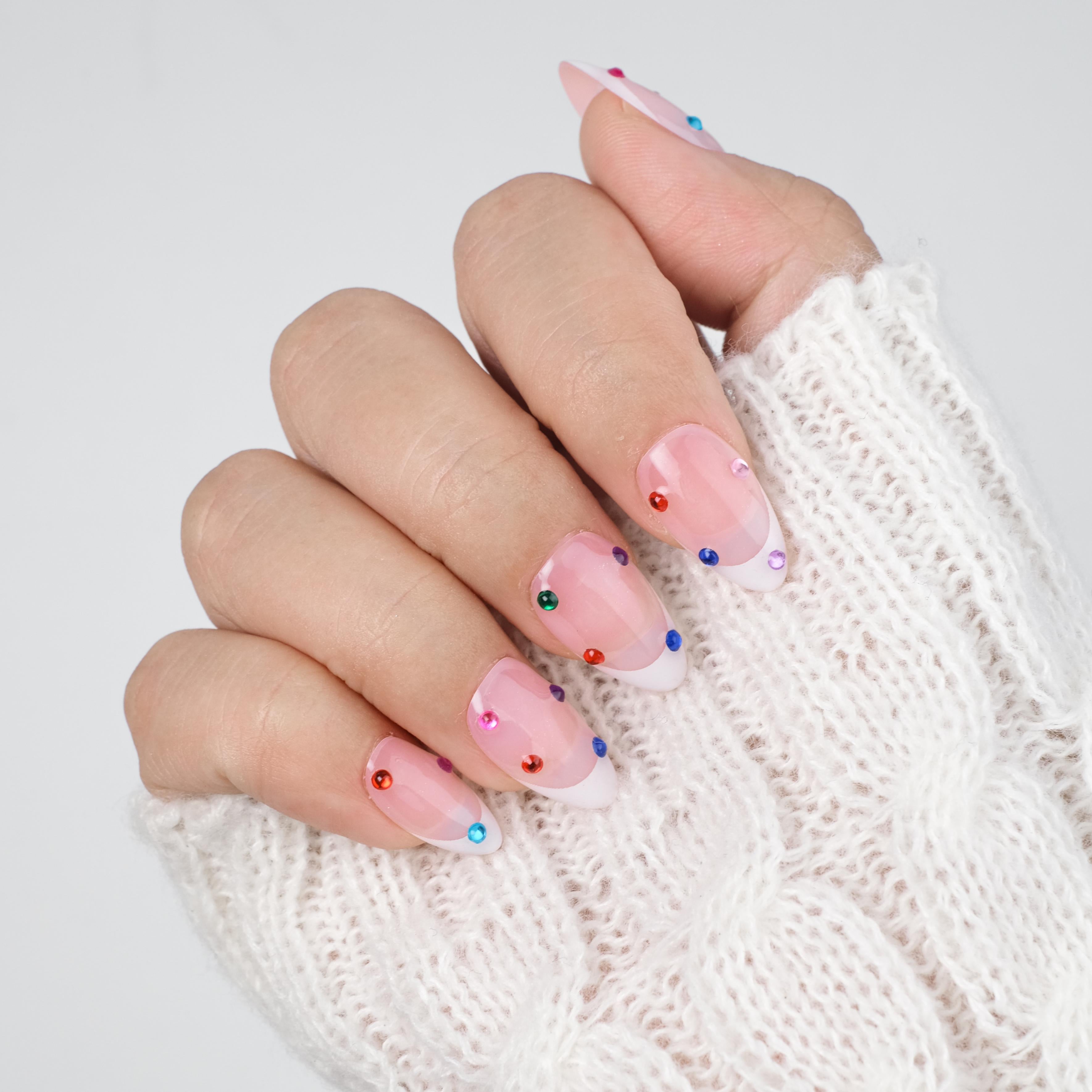 Nailique short almond press-on nails with nude base, white French tips, colorful rhinestones, and a soft gel finish. 26 reusable pieces.