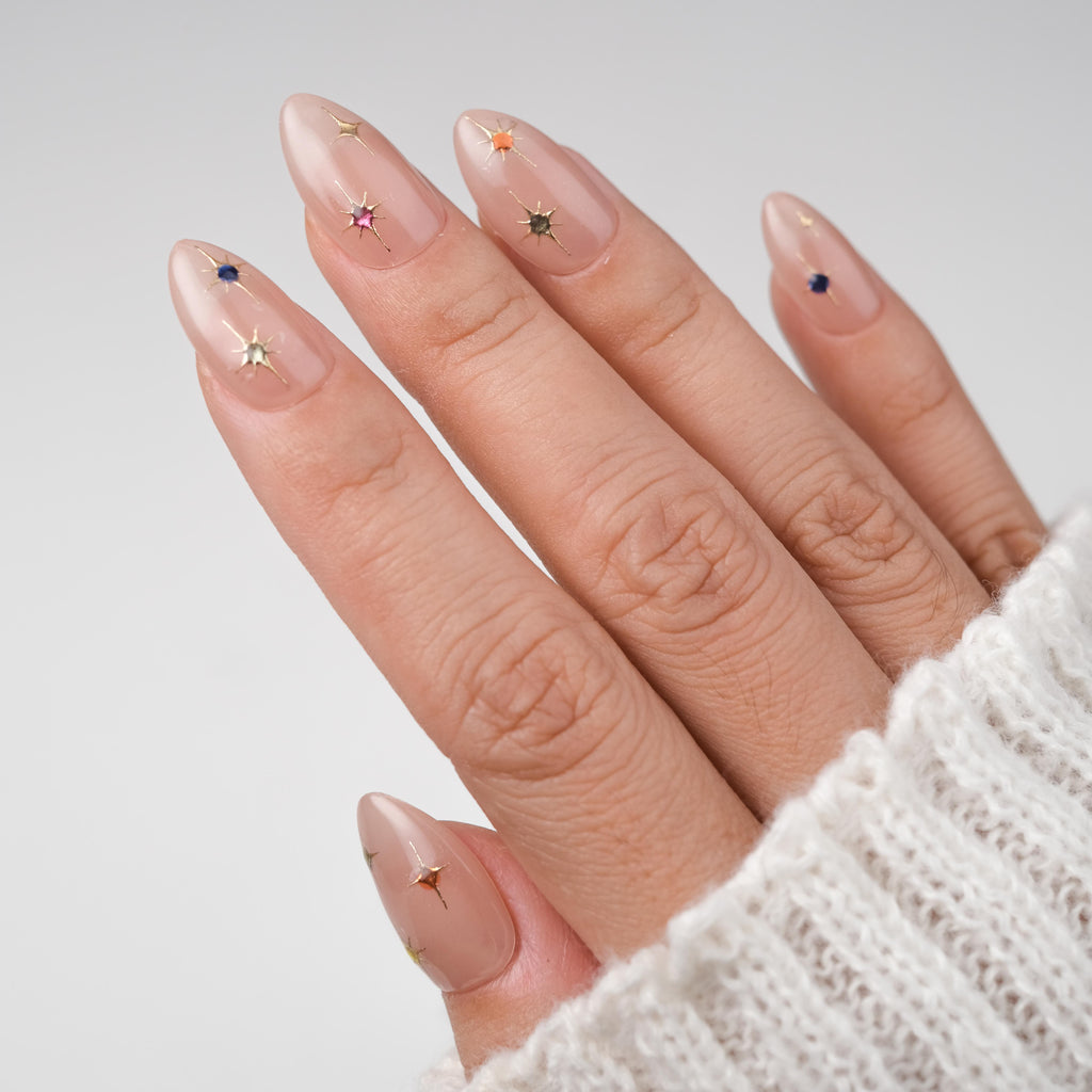 Nailique short almond press-on nails with nude pink base, gold star accents, and sparkle details, 26 reusable gel nail tips with glue.