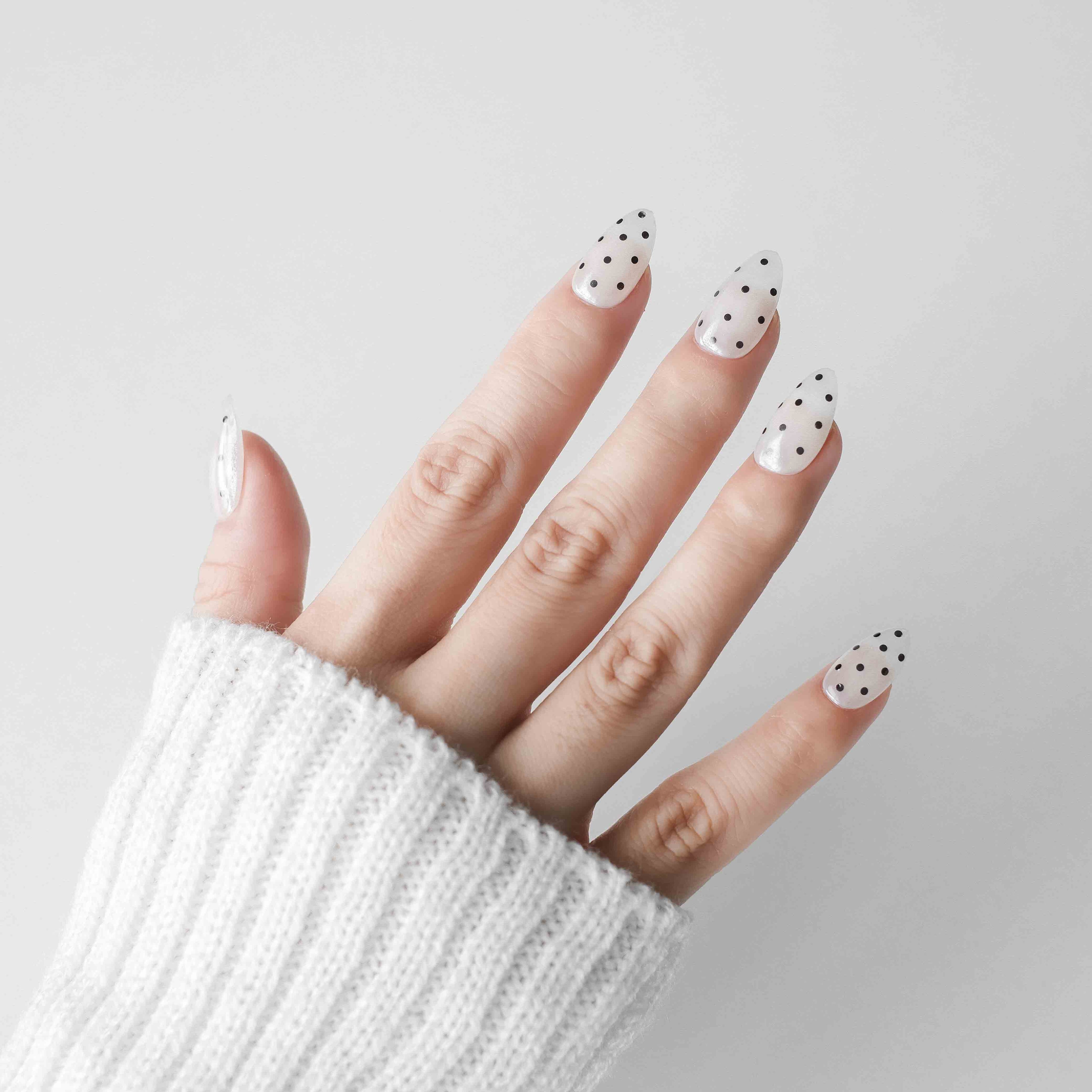 Handmade short almond press on nails from Nailique with chrome donut design, soft gel finish, white and black polka dot pattern.