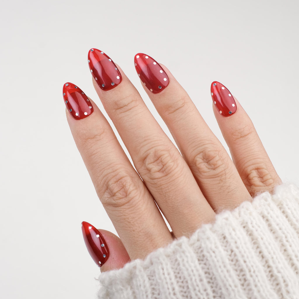 Short glossy red press-on nails with metallic studs, reusable gel tips, and polka dot design from Nailique salon quality manicure set.