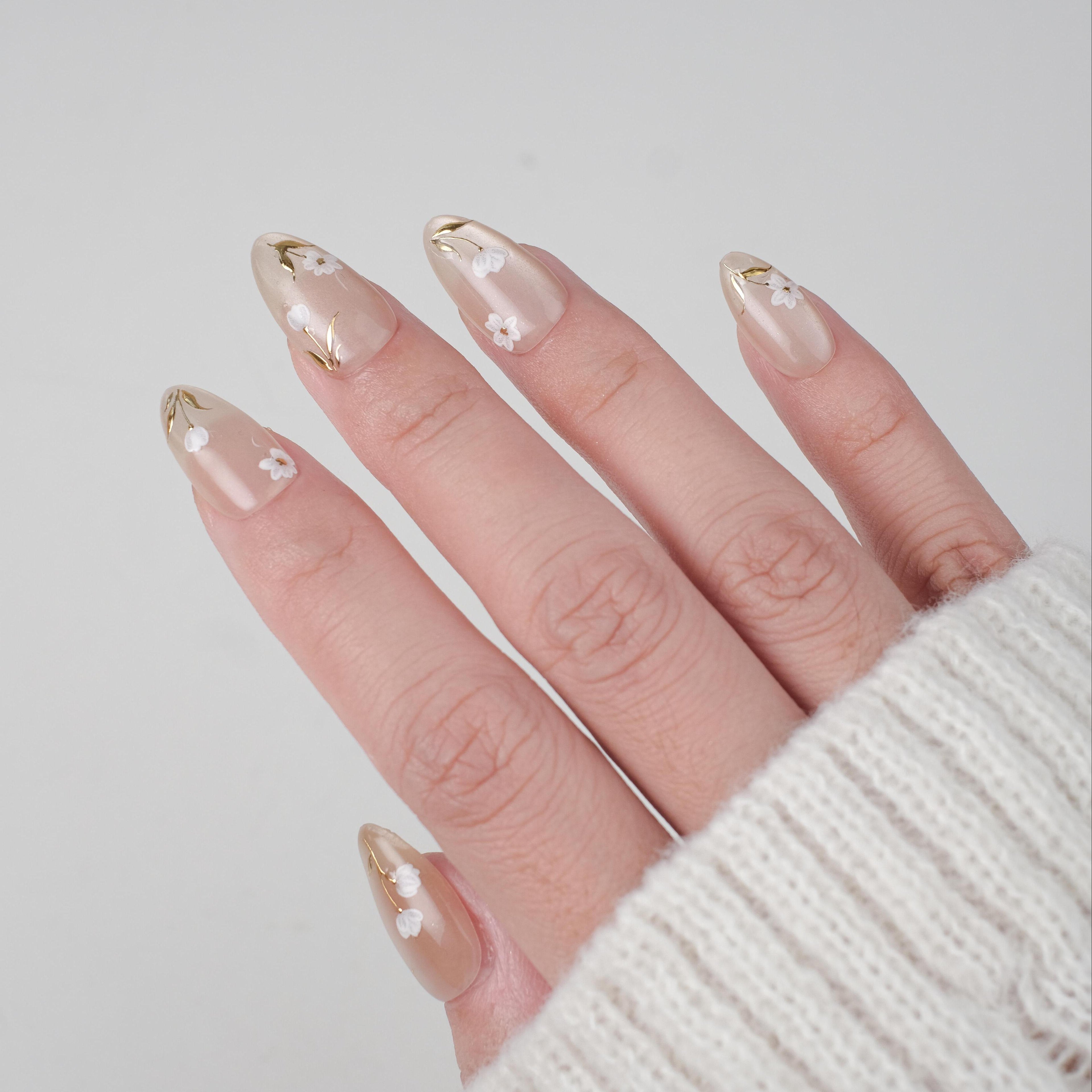 Handmade white floral short almond press on nails with gold foil design, reusable nail tips and lamp-curable glue from nailique.