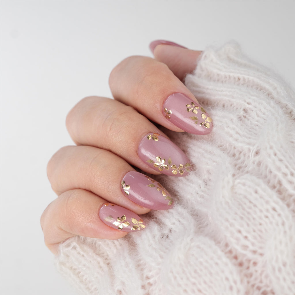Nailique short almond press-on nails with pink cat eye gel, gold foil floral design, reusable tips, glue, and remover.