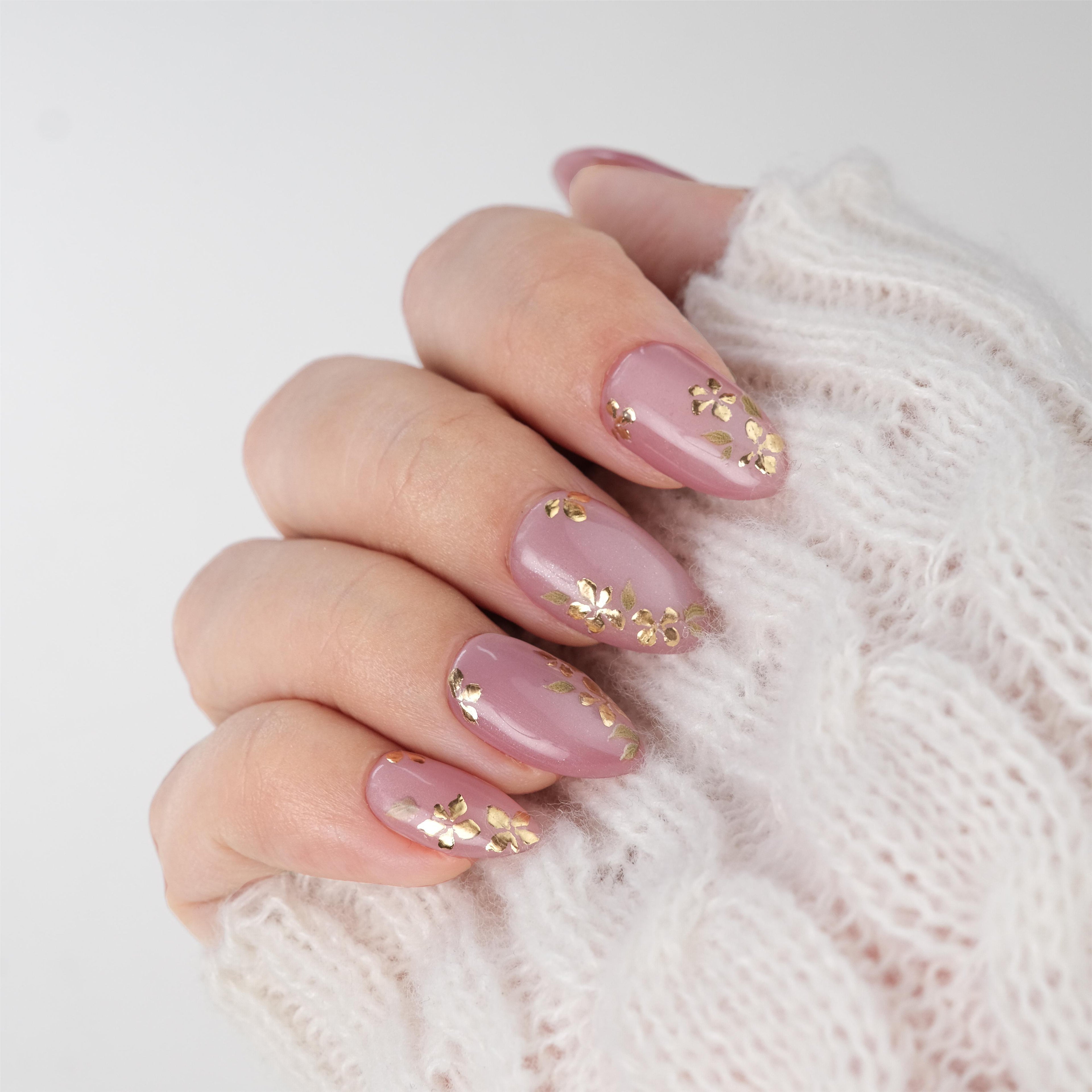 Nailique short almond press-on nails with pink cat eye gel, gold foil floral design, reusable tips, glue, and remover.
