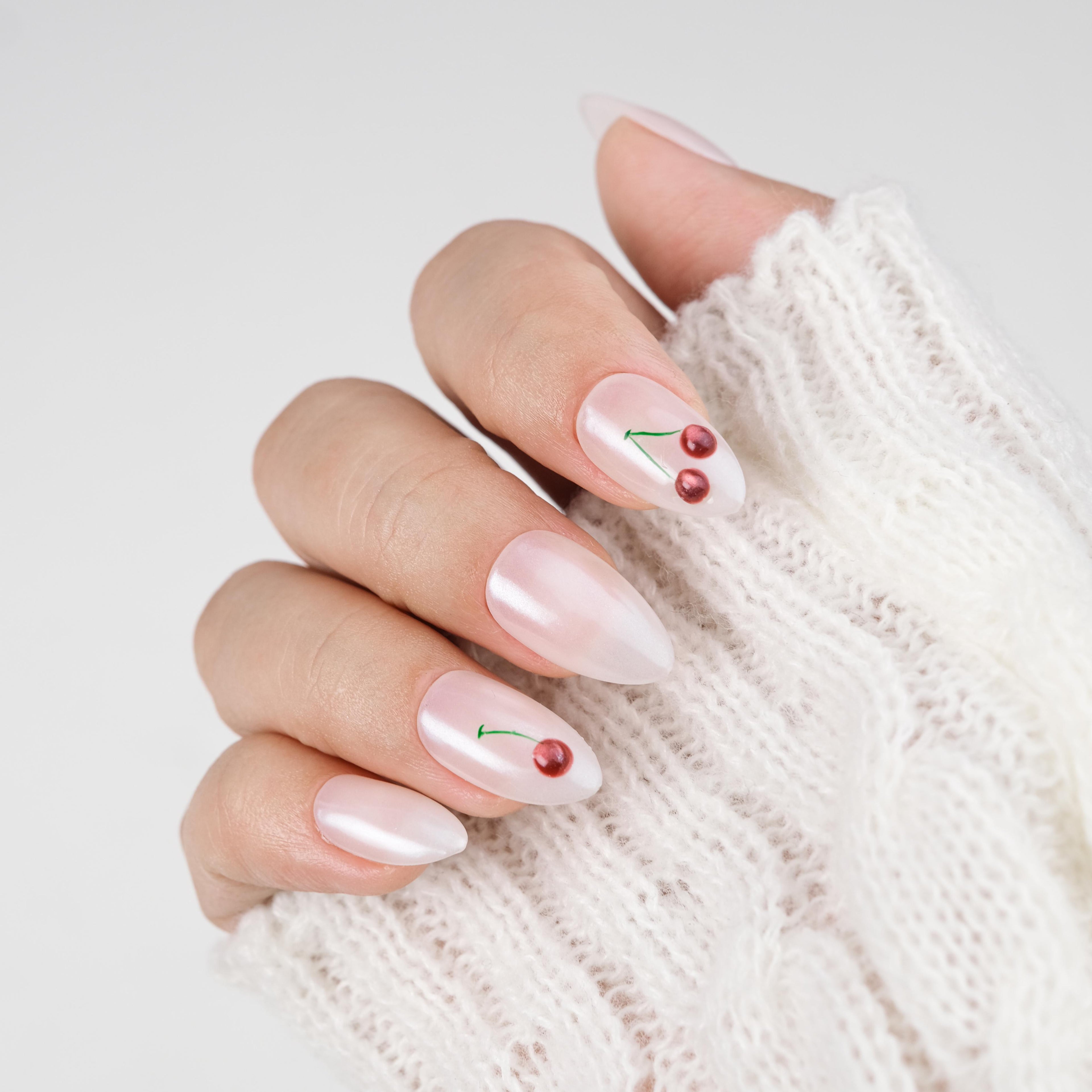 Handmade short almond press on nails by Nailique with 3D cherry design, soft gel, milky pearl finish, reusable with glue and remover.