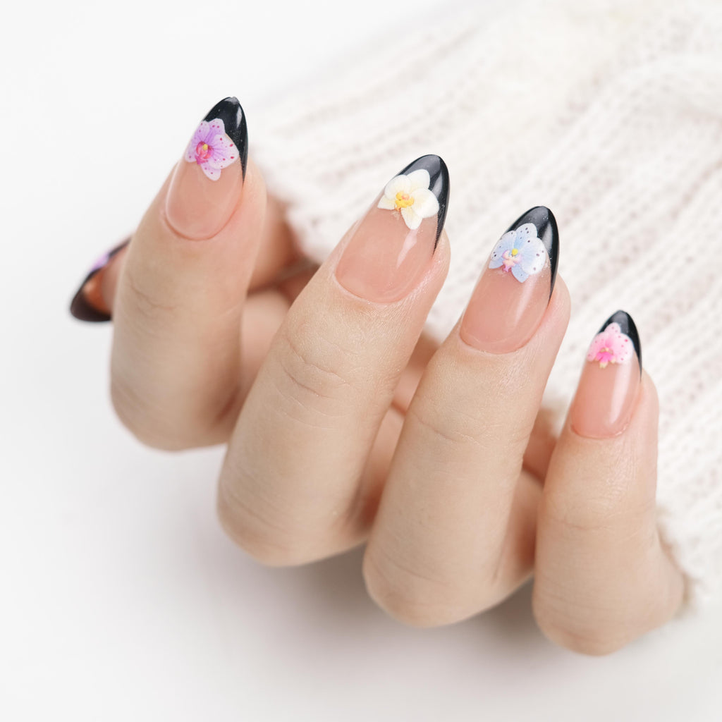 Short almond press-on nails by Nailique with black French tips and 3D orchid flower art, reusable gel fake nails, summer manicure.