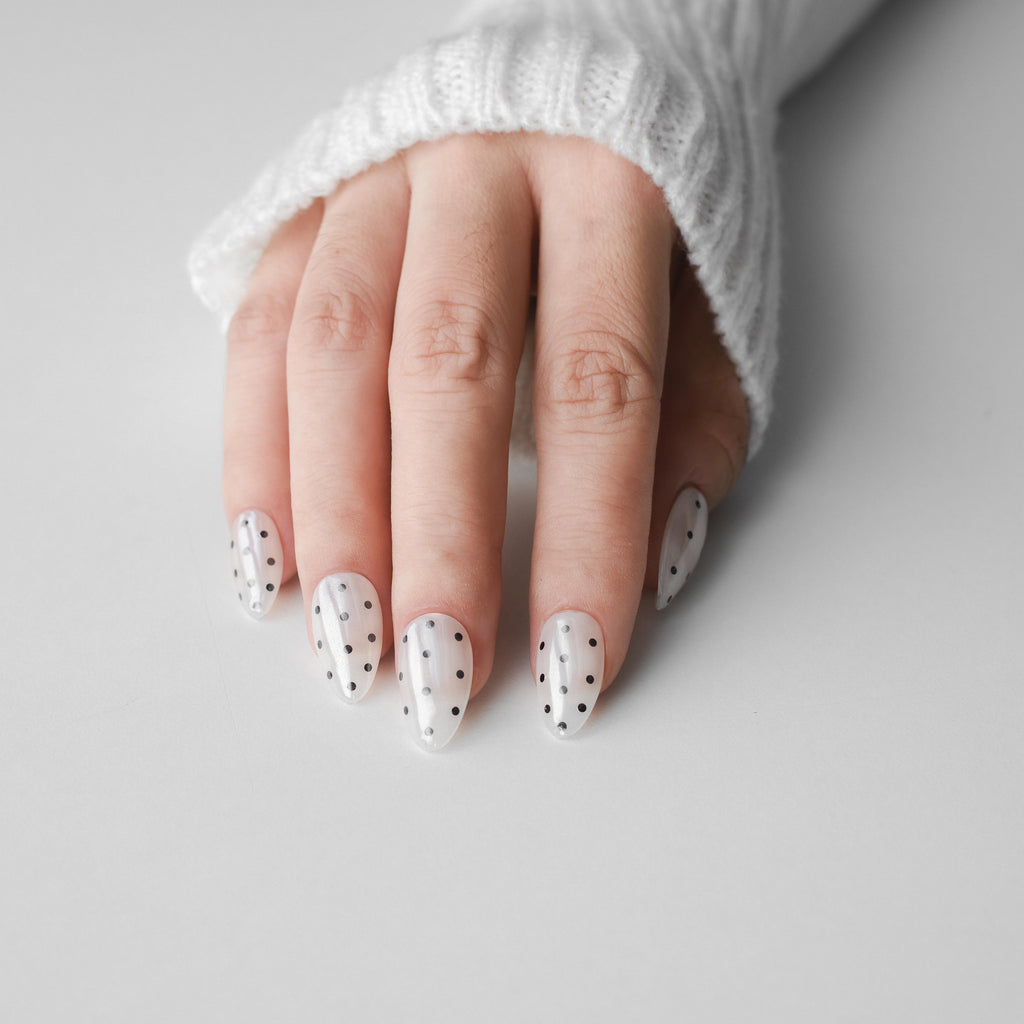 Handmade short almond press-on nails by Nailique with chrome glaze, donut design, soft gel finish, white and black polka dots.