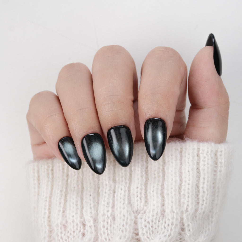 Handmade short almond press-on nails by Nailique featuring midnight blue cat eye soft gel with black shimmer, 26 reusable tips with glue and remover