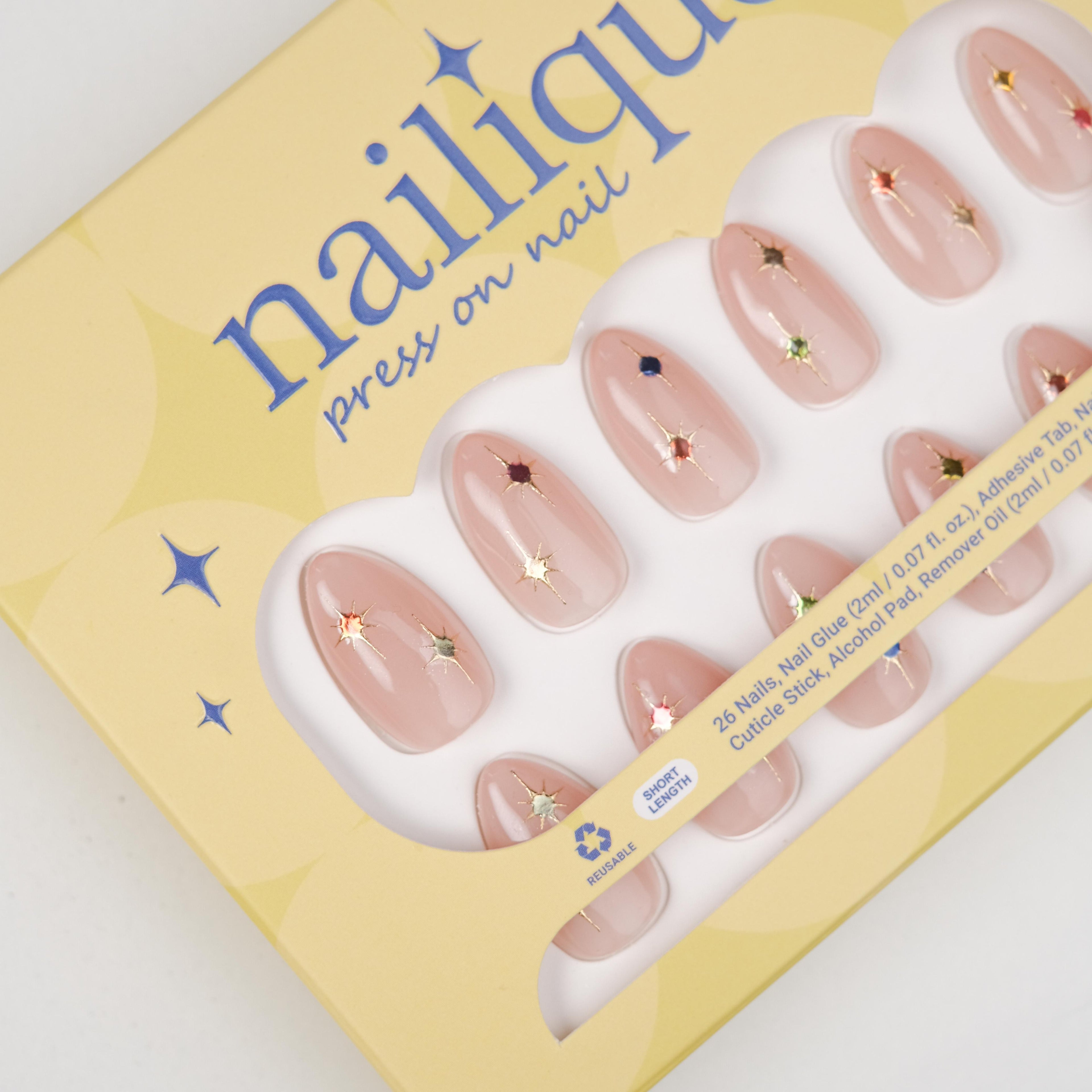 Short almond press-on nails by Nailique featuring soft nude pink gel finish, gold star accents, and colorful sparkle details.