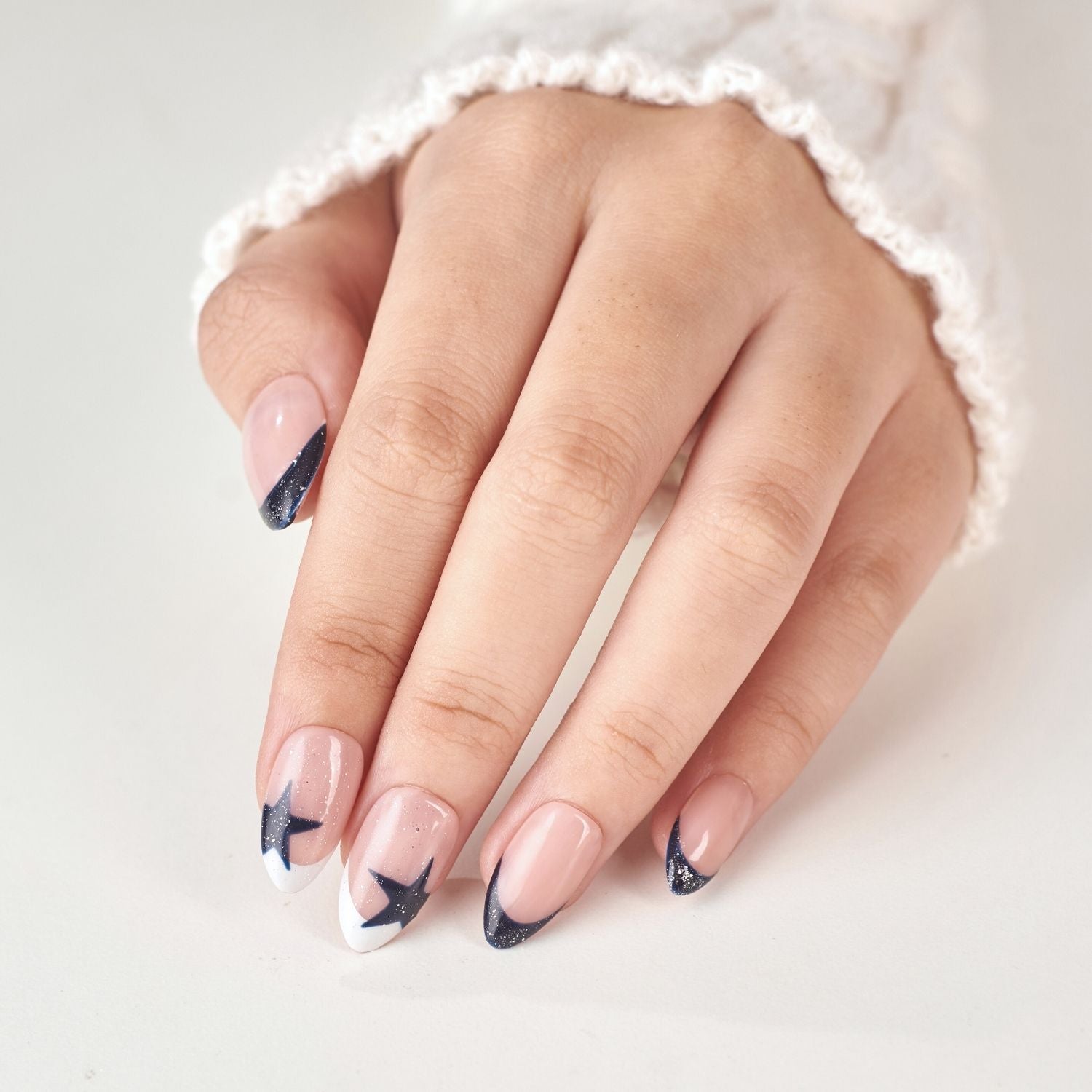 Handmade navy blue short almond press-on nails with French tip, star glitter shimmer, soft gel finish by Nailique.