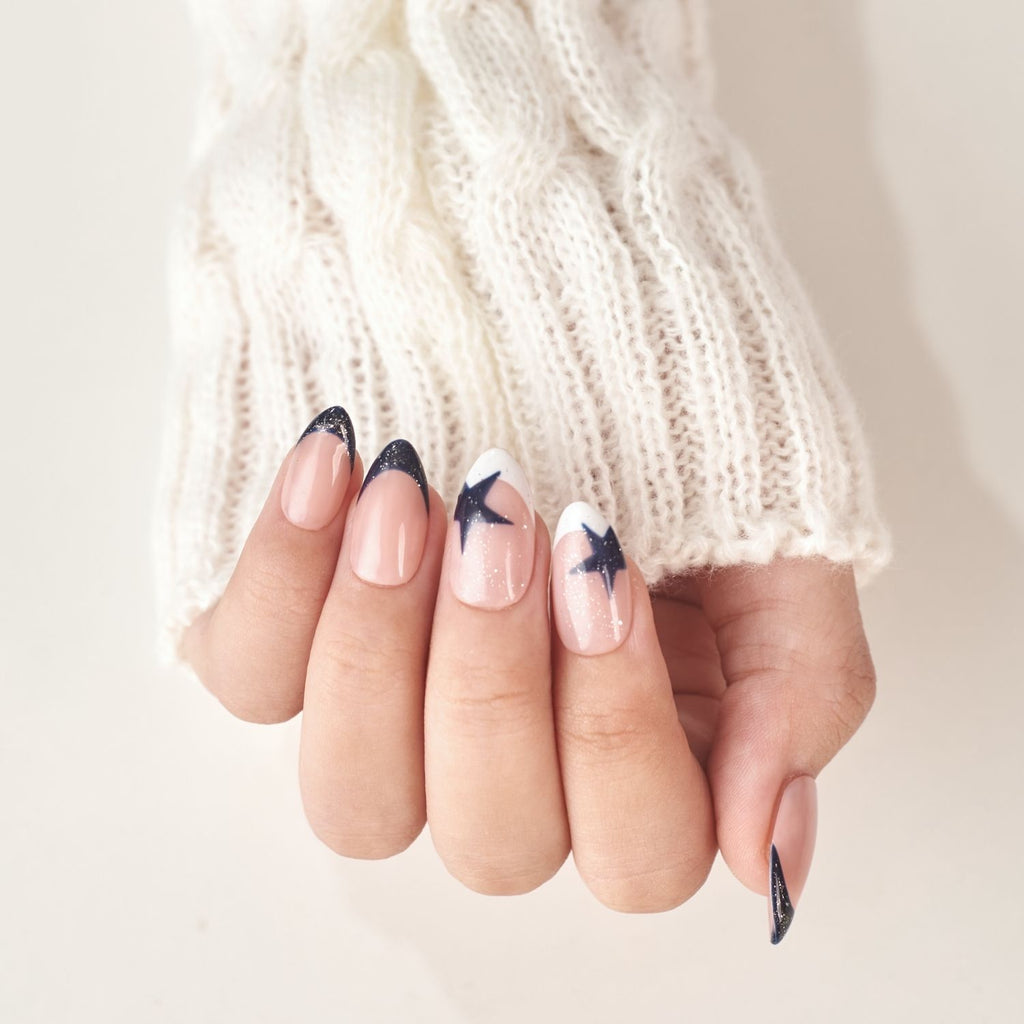Short almond press-on nails by Nailique featuring navy blue French tips, soft gel finish, star glitter shimmer, and handmade design.