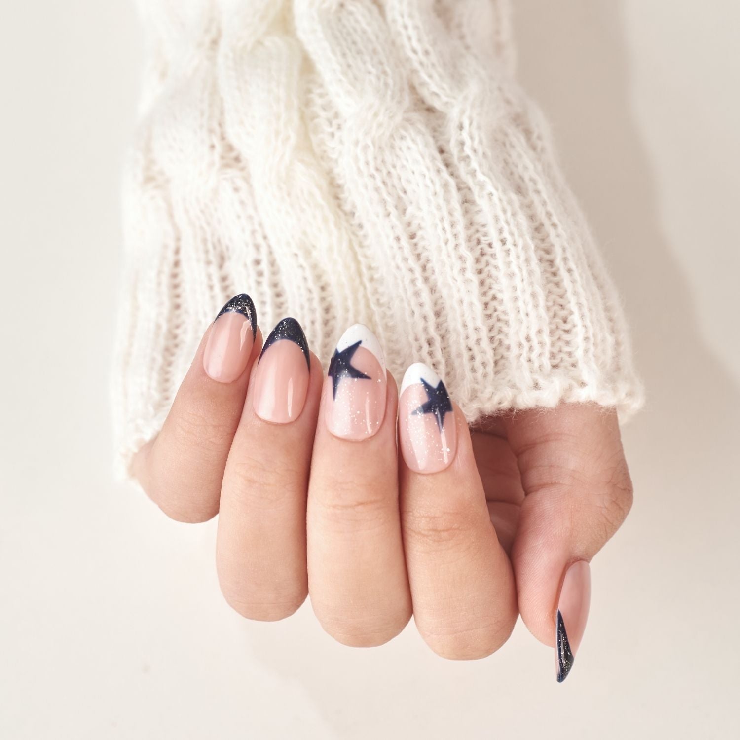 Short almond press-on nails by Nailique featuring navy blue French tips, soft gel finish, star glitter shimmer, and handmade design.