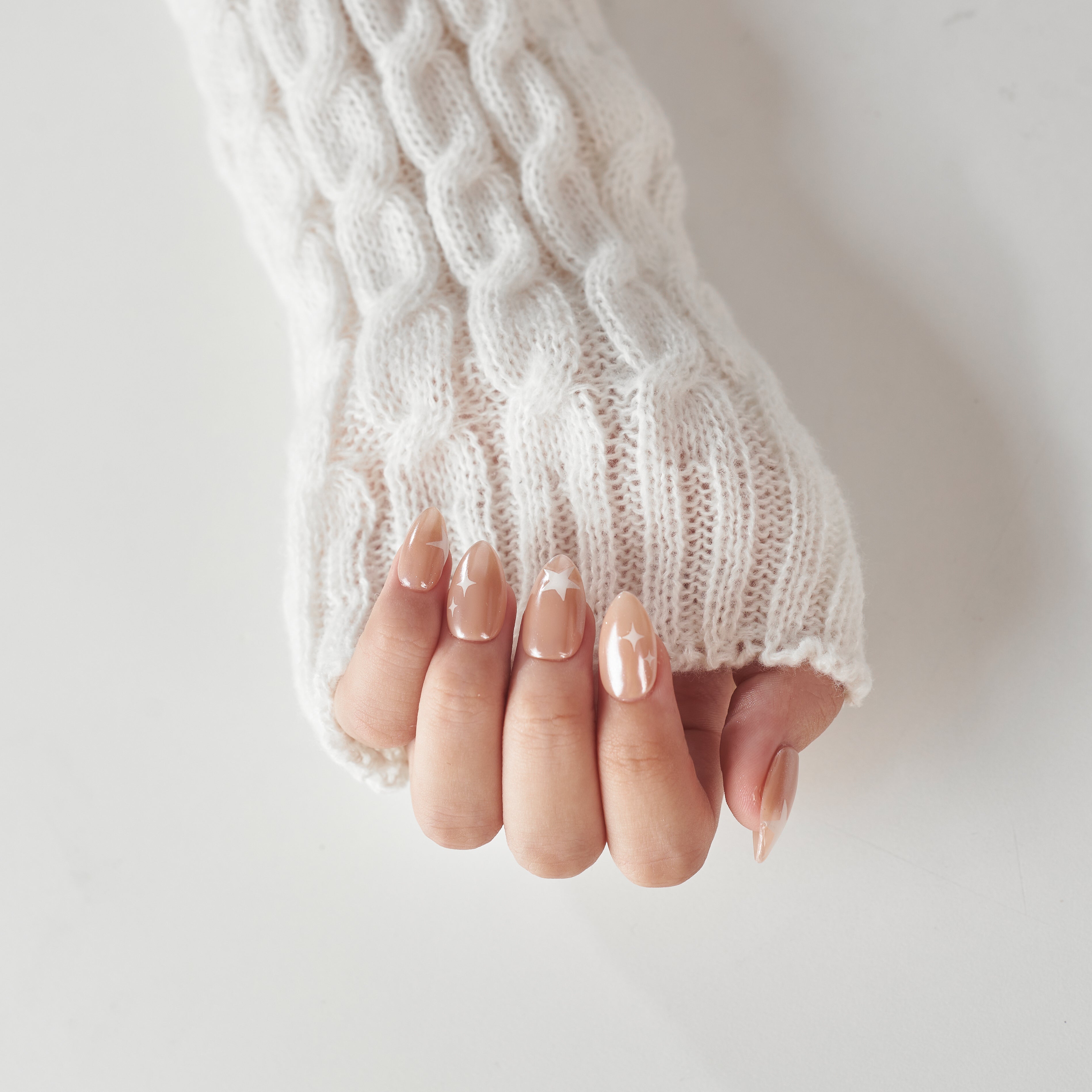 Short almond-shaped press on nails by Nailique featuring chrome glaze, soft gel finish, nude color, and star design.