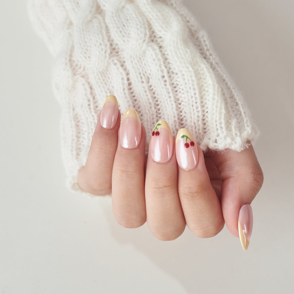 Short almond press-on nails by Nailique featuring handmade butter yellow with cherry glazed chrome French tips.